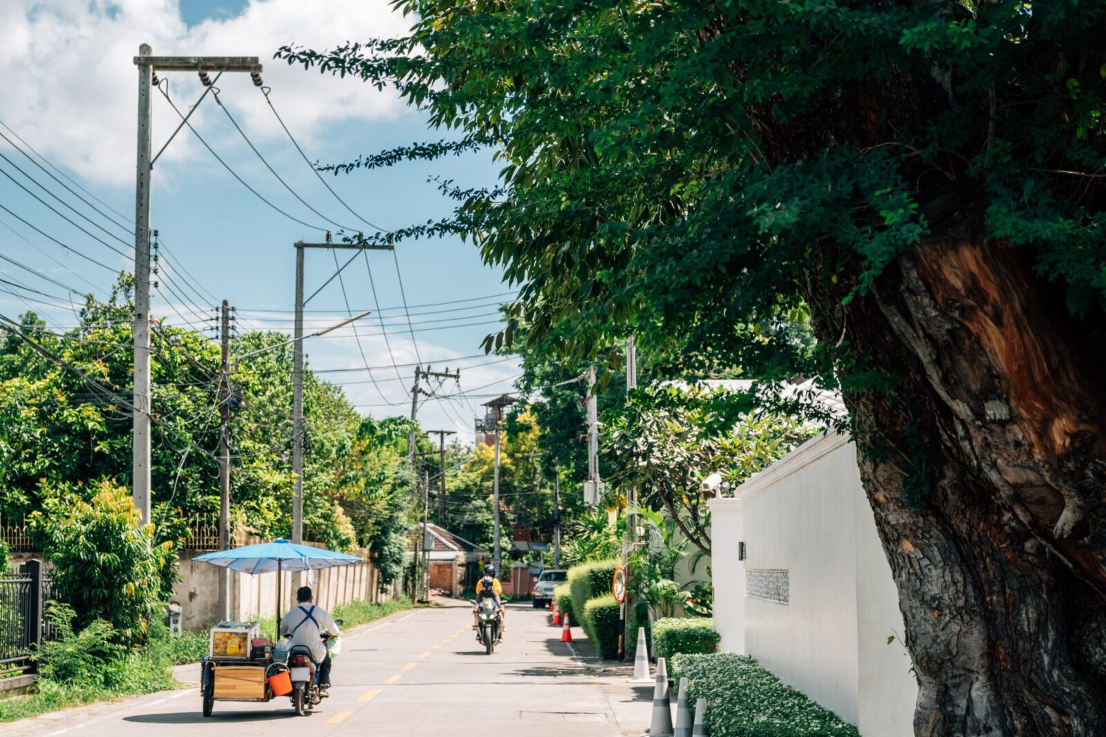 Quiet residential street in Thailand with greenery and motorbike, representing safest cities in Thailand for UK expats and peaceful living environment.