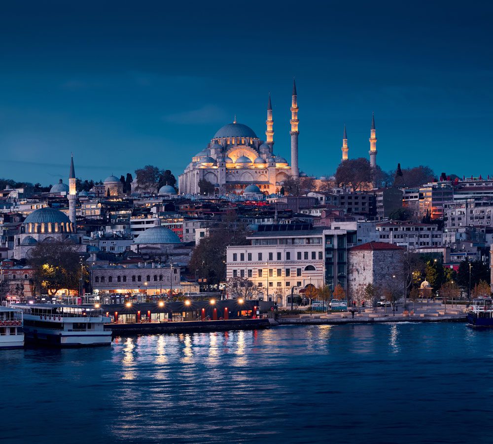 Panoramic view of Istanbul skyline at sunset overlooking the Bosphorus, featuring the Süleymaniye Mosque and Turkey's historic waterfront.