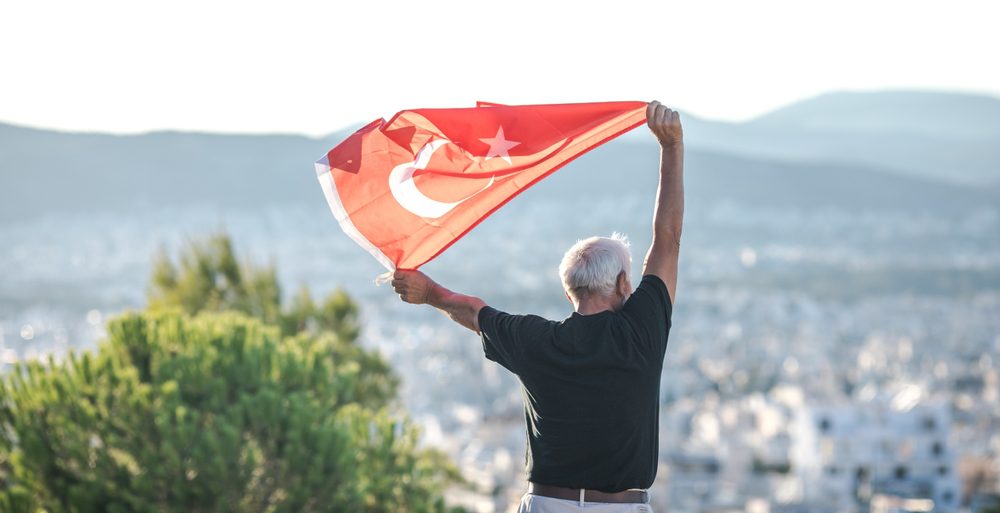 Person holding the Turkish flag overlooking a city while beginning a new life in Turkey. 